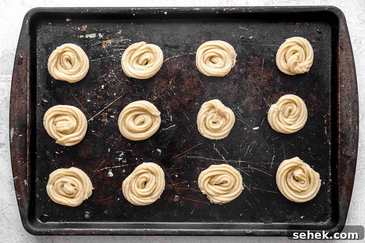 Classic Homemade Butter Cookies Recipe for Crisp, Melt-in-Your-Mouth Cookies 9 Unbaked cookies lined up on a baking sheet.