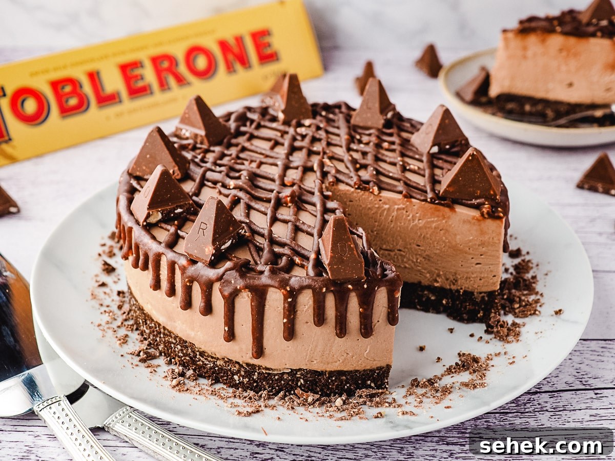 Decadent Toblerone Cheesecake Recipe with Crunchy Chocolate Honeycomb 3 Whole cheescake on a plate, with slice on a plate and Toblerone in background.
