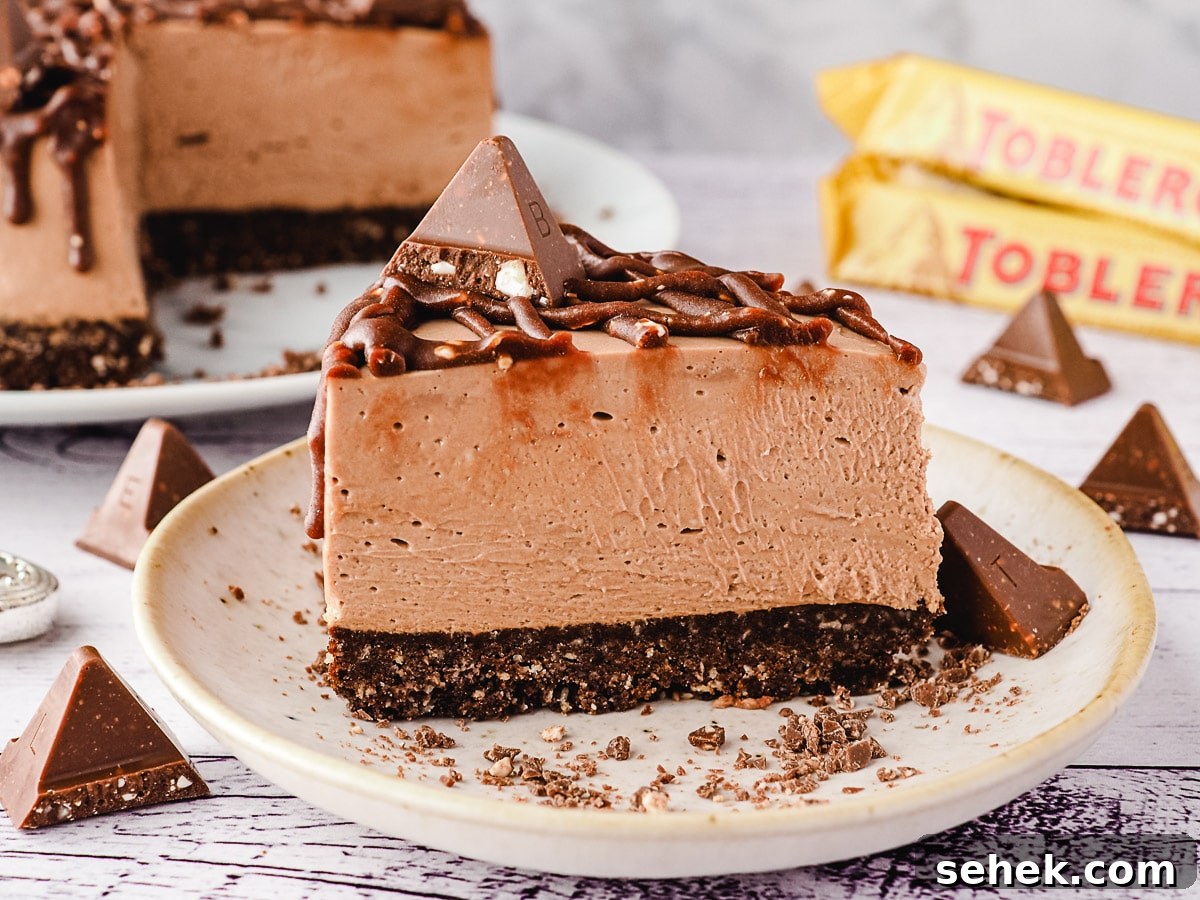 Decadent Toblerone Cheesecake Recipe with Crunchy Chocolate Honeycomb 9 Slice of Toblerone cheesecake on a plate, with rest of cheesecake and more Toblerone in background.