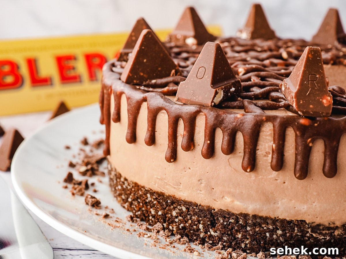 Decadent Toblerone Cheesecake Recipe with Crunchy Chocolate Honeycomb 10 Close-up side view of whole cheesecake showing drip, with Toblerone in background.