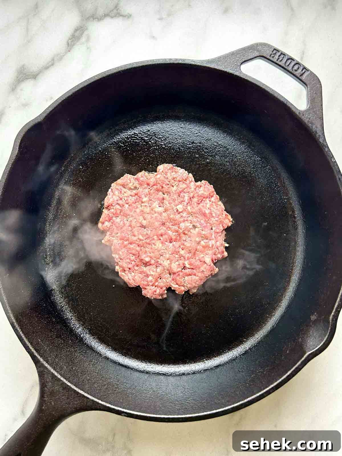 raw patty on cast iron pan