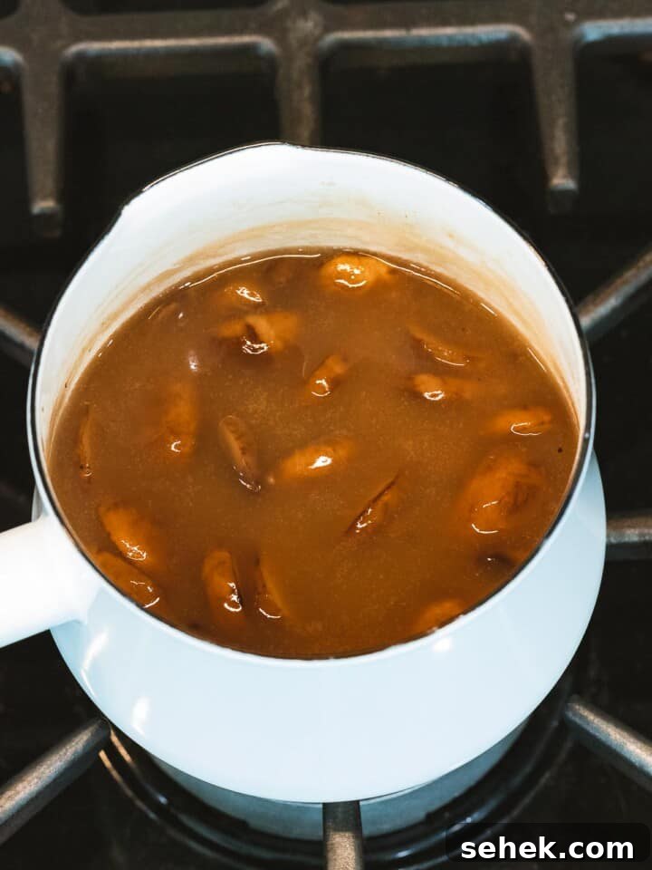 Creamy Mushroom Gravy Recipe for Steaks and Mashed Potatoes 9 Mushroom gravy with added mushrooms cooking in a pot.
