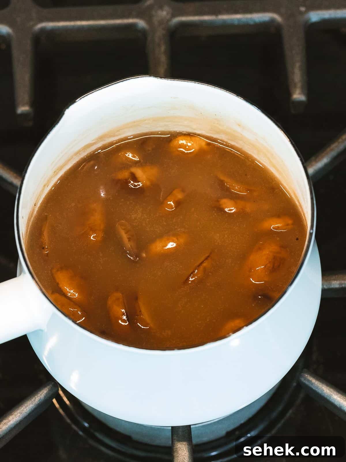 Creamy Mushroom Gravy Recipe for Steaks and Mashed Potatoes 5 Mushroom gravy with added mushrooms cooking in a pot.