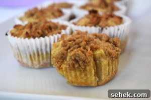 Fluffy Apple Cinnamon Muffins with Streusel Topping 2 Apple crumb muffin on a white plate.
