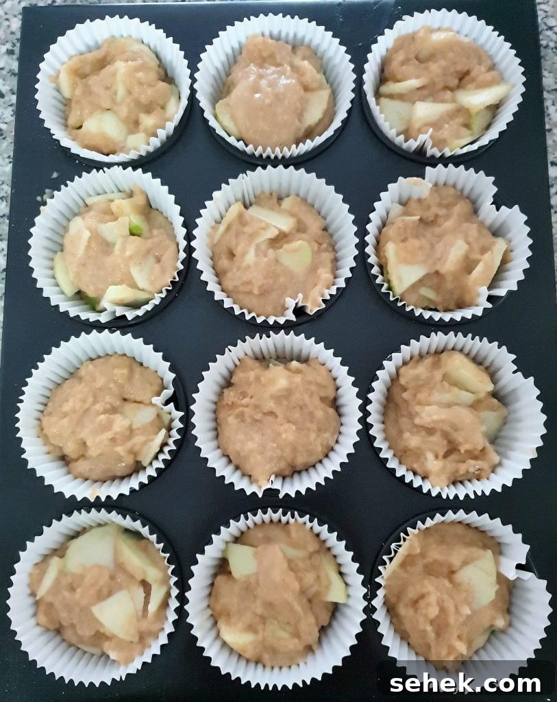 Fluffy Apple Cinnamon Muffins with Streusel Topping 13 Apple cinnamon muffins in muffin cases.