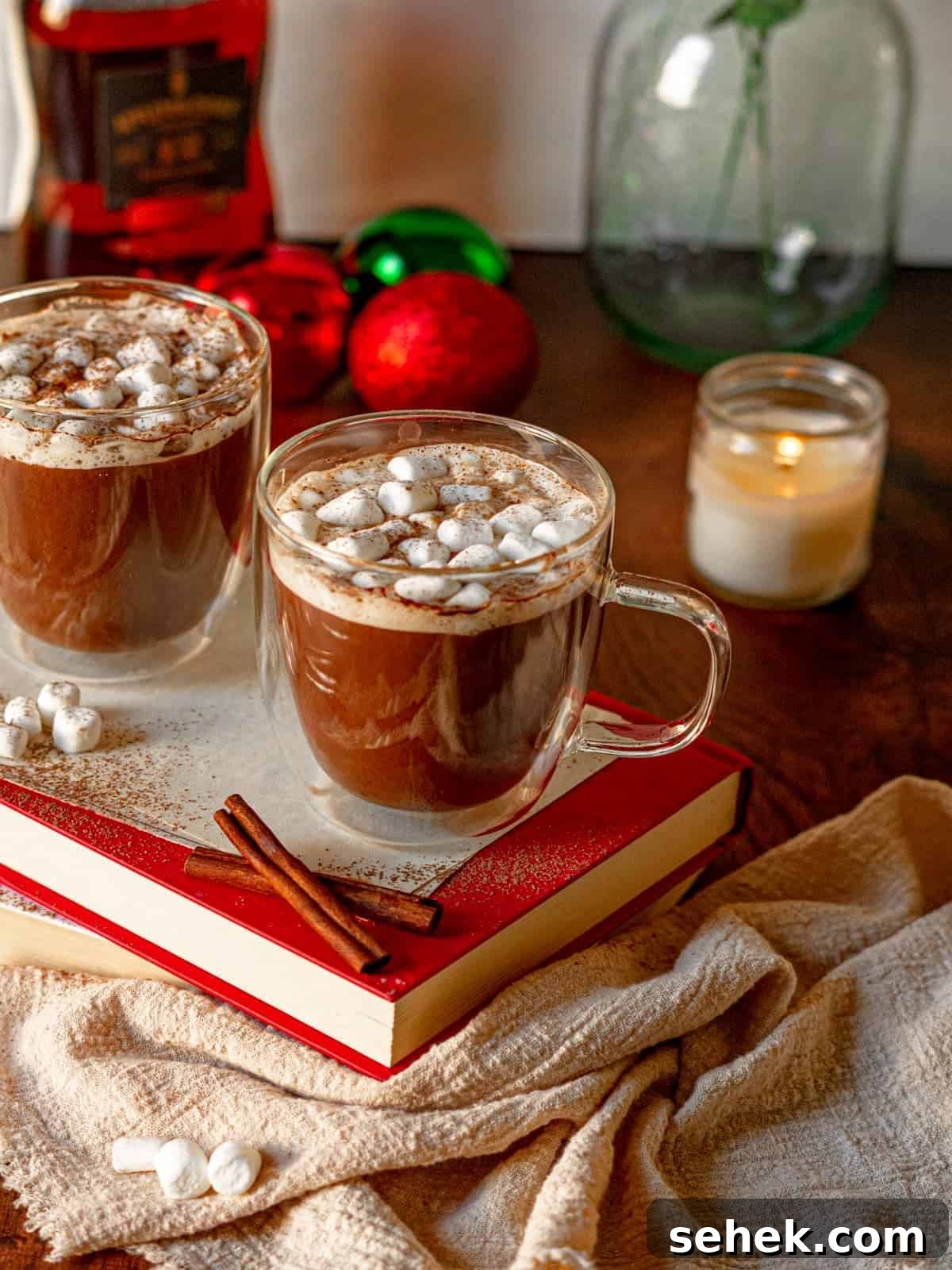 Dairy-Free Spiked Hot Chocolate Recipe: Cozy Vegan Cocoa with Rum 2 Clear mugs filled with spiked hot chocolate on a stack of books.