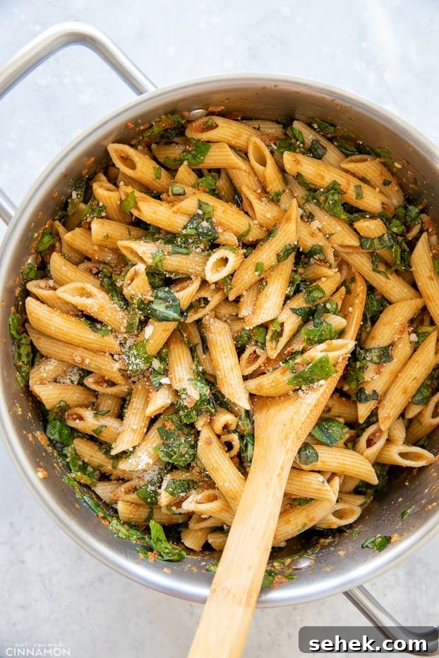 Sun-Dried Tomato Pasta with Garlic and Basil Sauce 8 overhead shot of a pot with sun-dried tomato pasta with spinach and parmesan with a wooden spoon