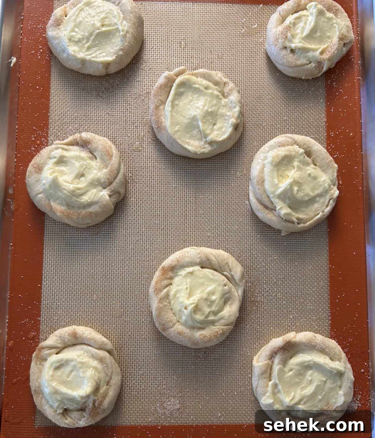 Cream cheese danish with egg wash and cinnamon and sugar on baking tray.