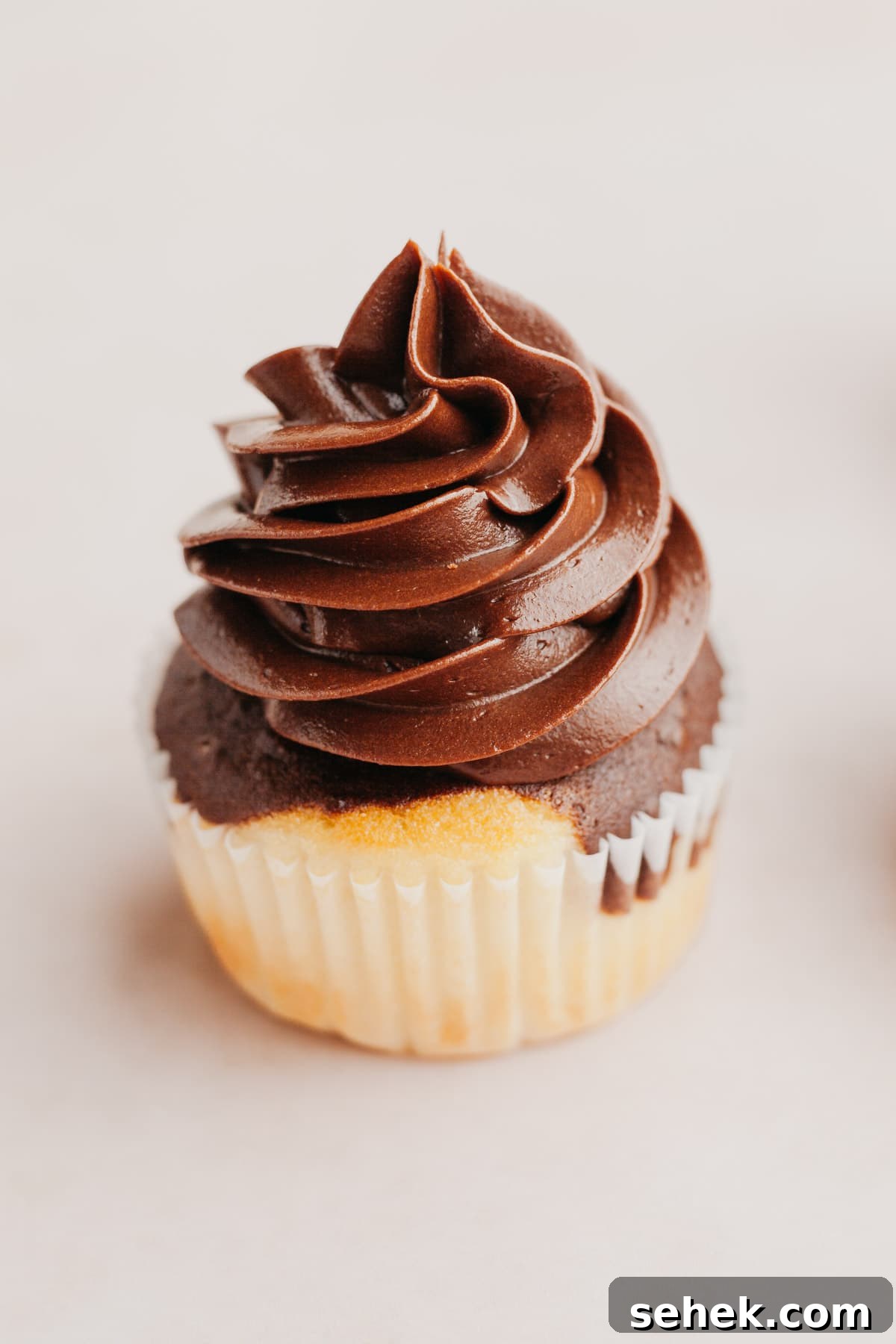 Whipped Chocolate Ganache Frosting Recipe for Cakes 7 A close up of a cupcake with piped chocolate whipped ganache frosting.