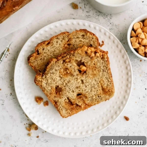 Two slices of Banana Bread on a small white plate with a cup of milk and a small cup of butterscotch chips on the side.