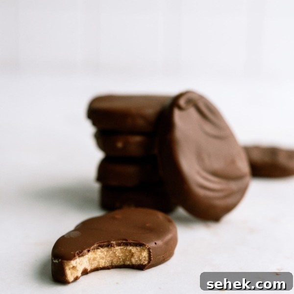 Homemade Reese’s Eggs stacked with one of to the side with a bite missing.
