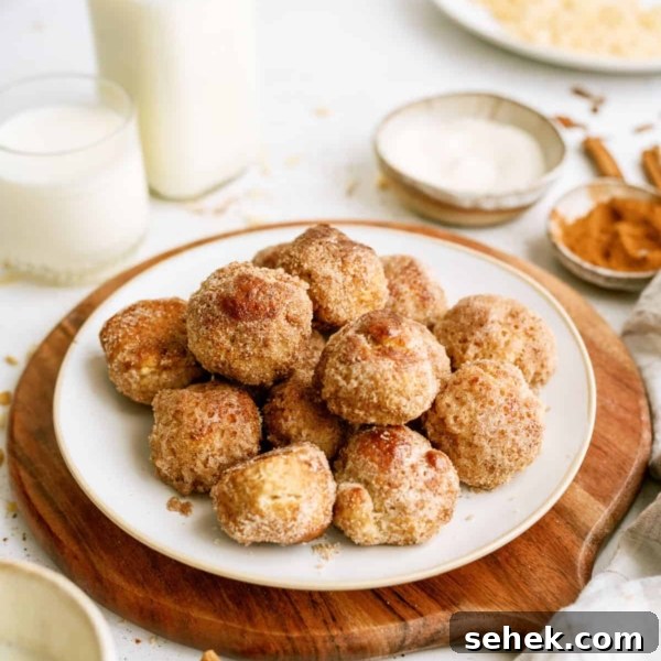 Cinnamon breakfast bites stacked on a plate with a cutting board underneath. A glass of milk and a bottle of milk on the side.