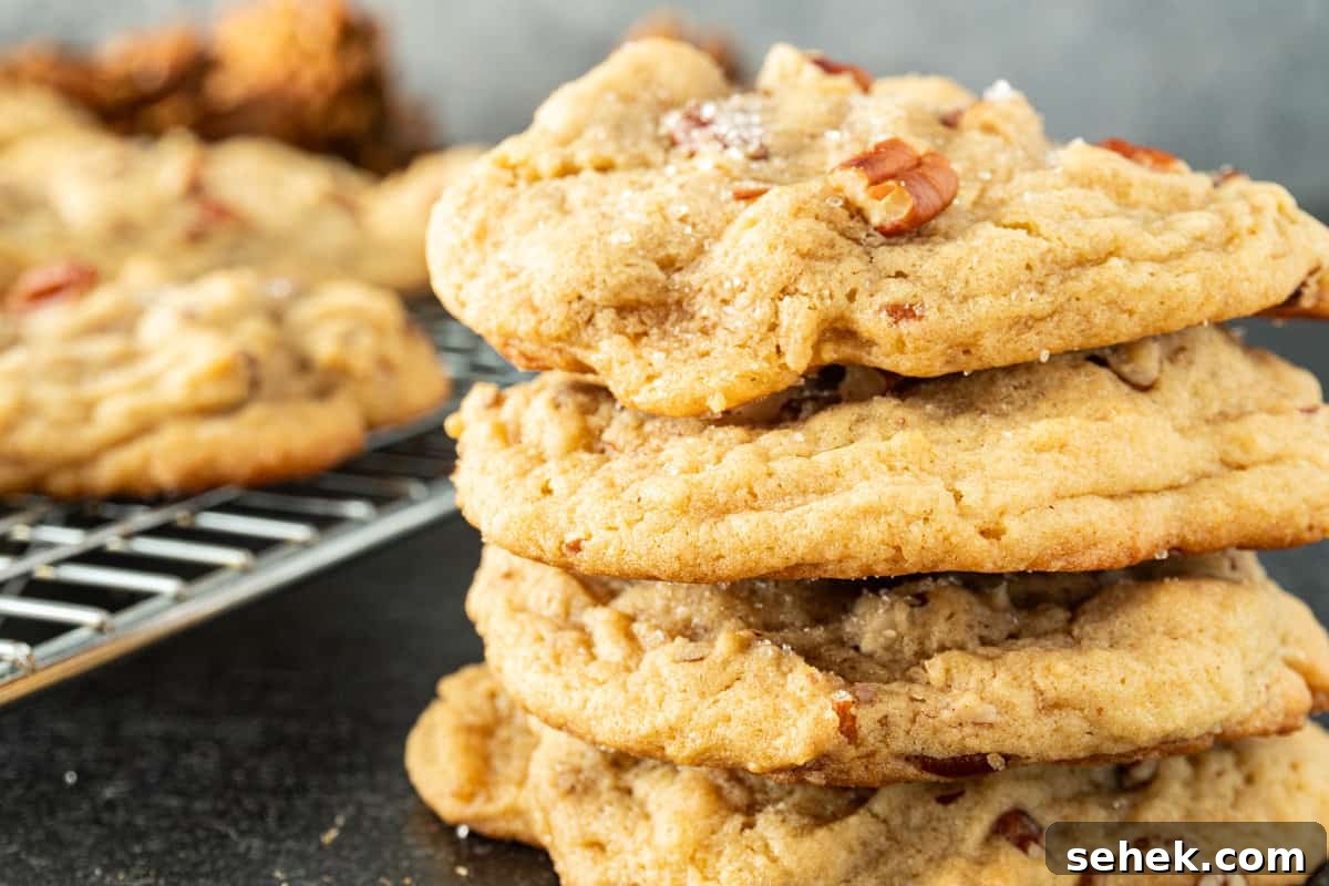 Pecan Pie Cookies: Chewy Cinnamon-Pecan Cookie Recipe 12 stacked pecan pie cookies with more cookies in the background.