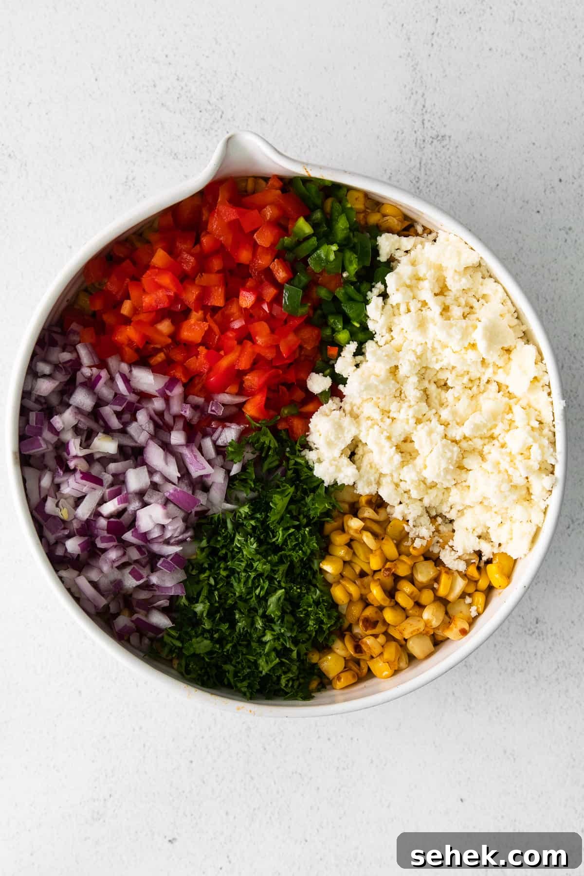 Cotija cheese is a white, crumbly Mexican cheese made from cow's milk and named after the town of Cotija, Mexico. Mexican corn salad ingredients in a bowl.