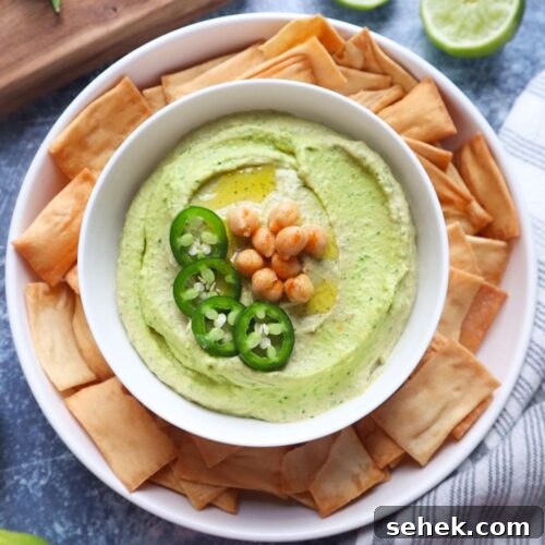 bowl with smooth jalapeno cilantro hummus surrounded by pita chips.