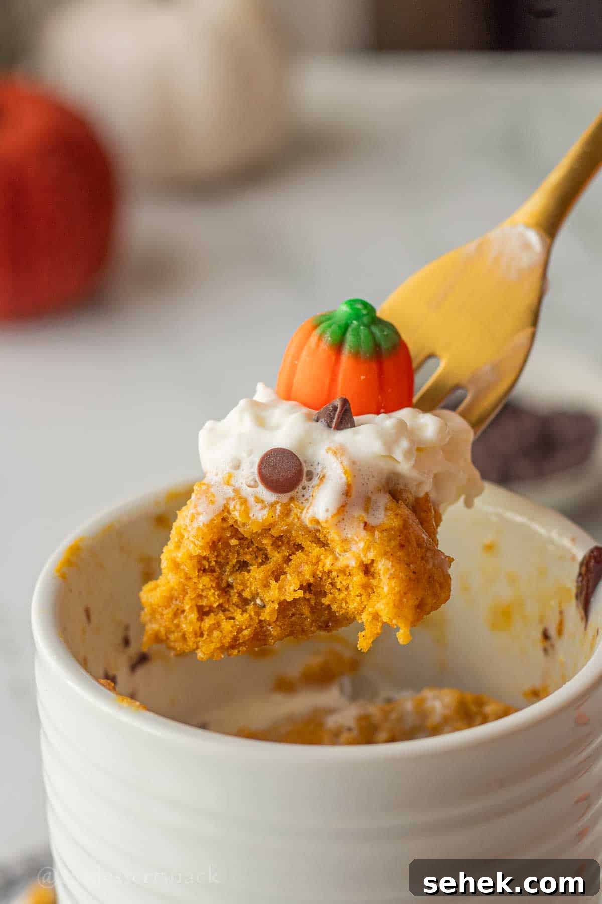 Quick Pumpkin Spice Mug Cake Recipe for One 2 Bite of spiced pumpkin mug cake on gold fork above mug.