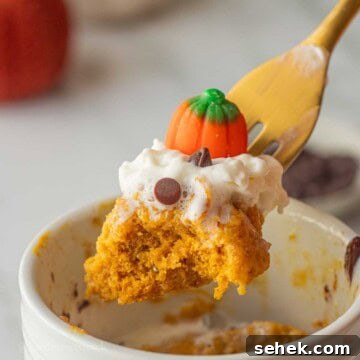 Quick Pumpkin Spice Mug Cake Recipe for One 11 Bite of spiced pumpkin mug cake on gold fork above mug.
