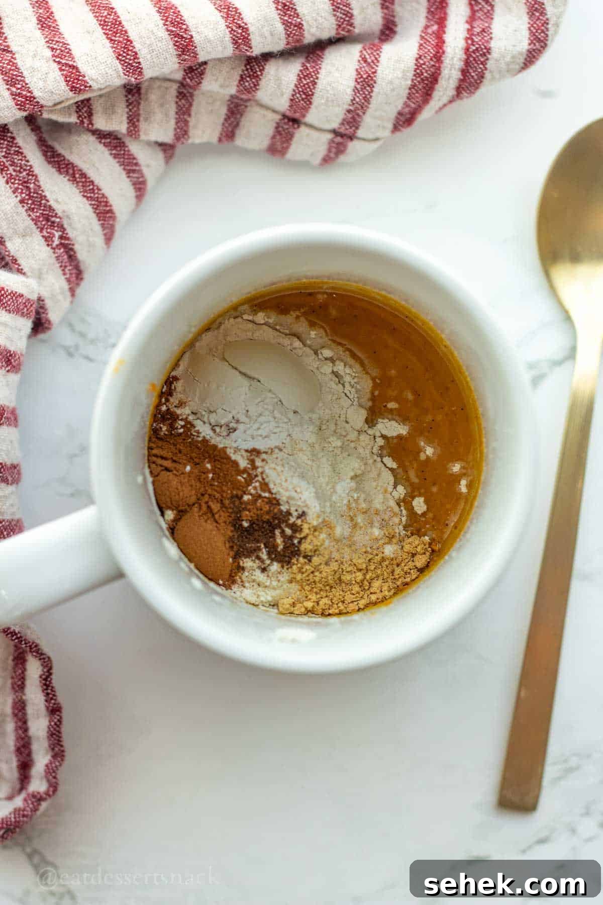Quick Pumpkin Spice Mug Cake Recipe for One 5 Dry ingredients on top of wet ingredients in mug.
