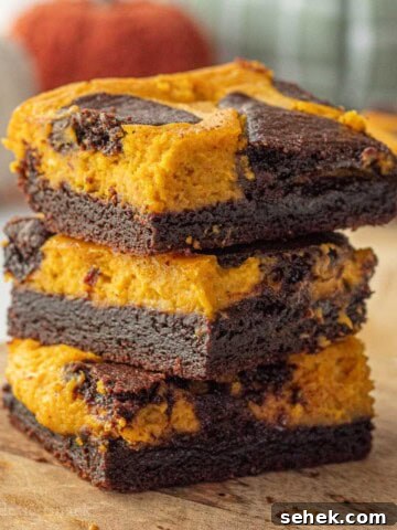 Stacked baked pumpkin cheesecake brownies.