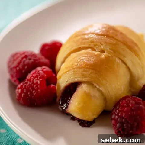 Raspberry brioche crescent on a plate with fresh raspberries