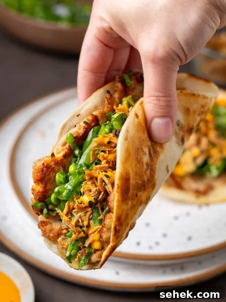 Seared ahi tuna smash taco with snap pea herb salad, crispy shallots, and sriracha mayo in a warm flour tortilla