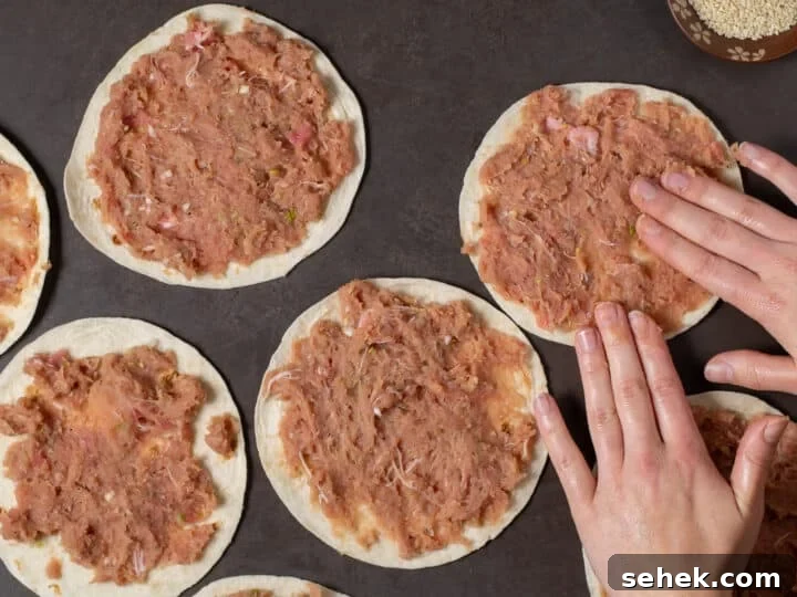 hands smashing ahi tuna mixture onto small flour tortillas