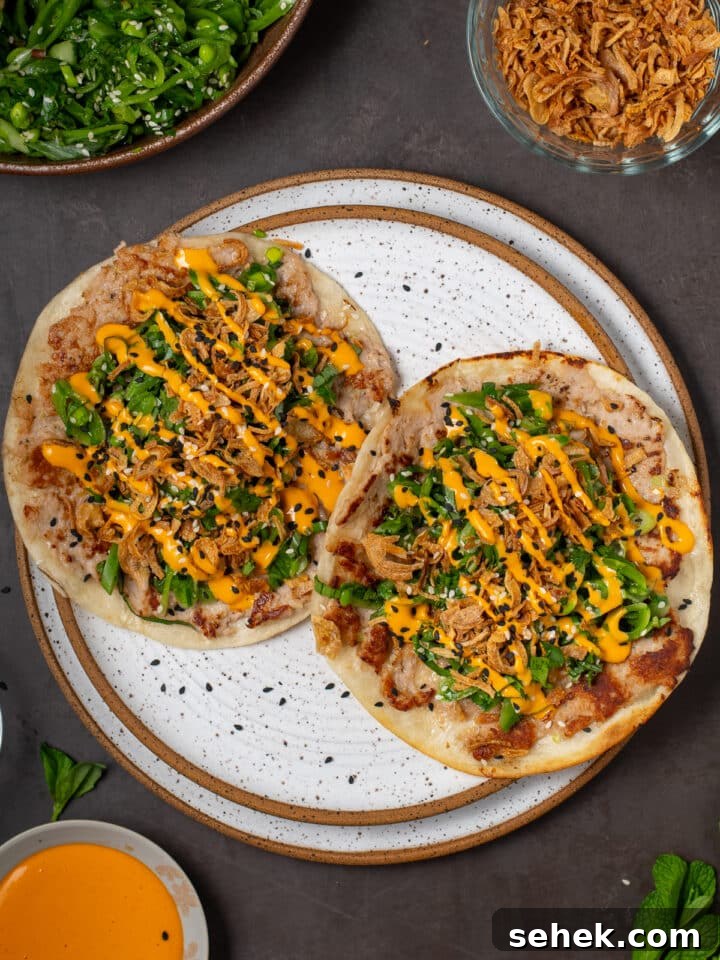 overhead view of two tacos on a white plate - seared ahi tuna tacos with snap pea salad with sriracha mayo drizzle