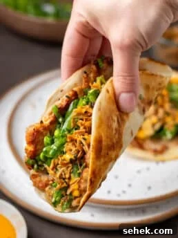 Seared ahi tuna smash taco with snap pea herb salad, crispy shallots, and sriracha mayo in a warm flour tortilla