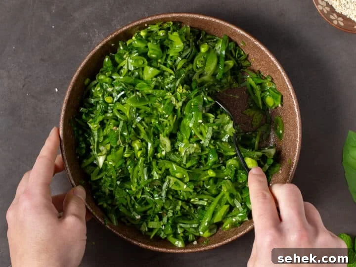 hands stirring together sesame snap pea salad