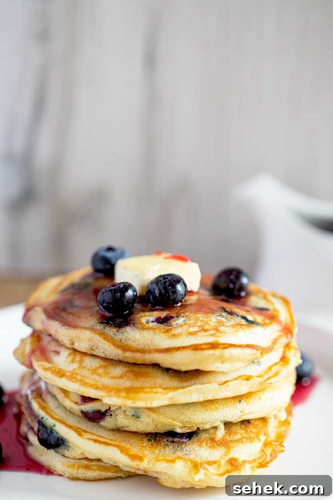 Fluffy Blueberry Pancakes (Made with Frozen Berries) 6 Super Fluffy Pancakes with blueberries stacked up high and drizzled with blueberry syrup and topped with butter.
