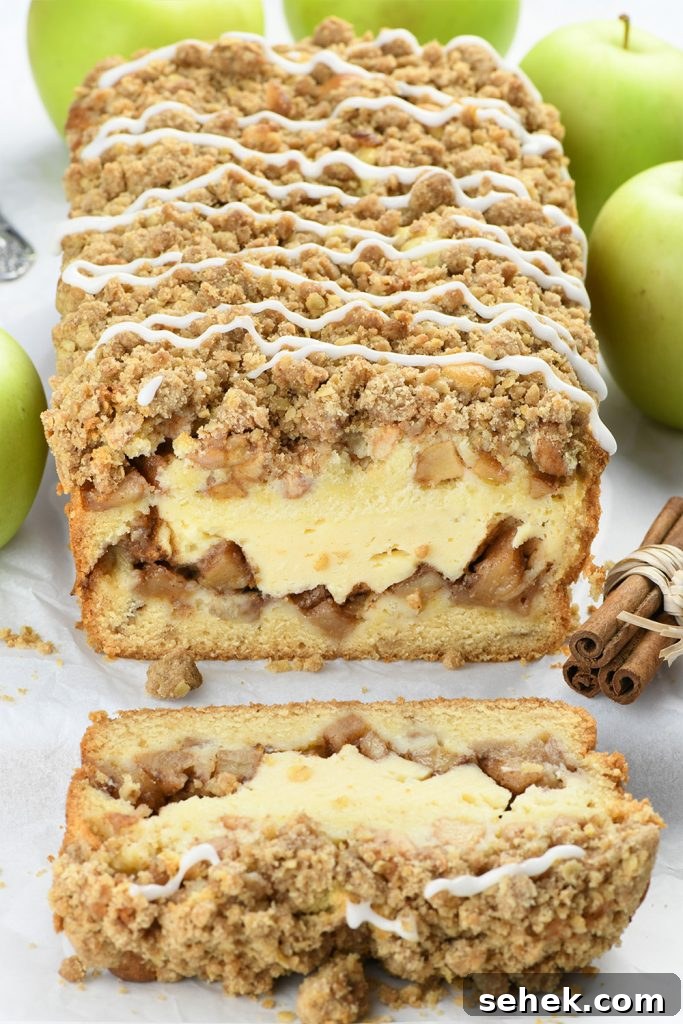 Apple Crisp Cheesecake Bread Recipe — Decadent Fall Dessert 3 Loaf of Apple Crisp Cheesecake Bread on a white parchment paper with bunch of green apples.