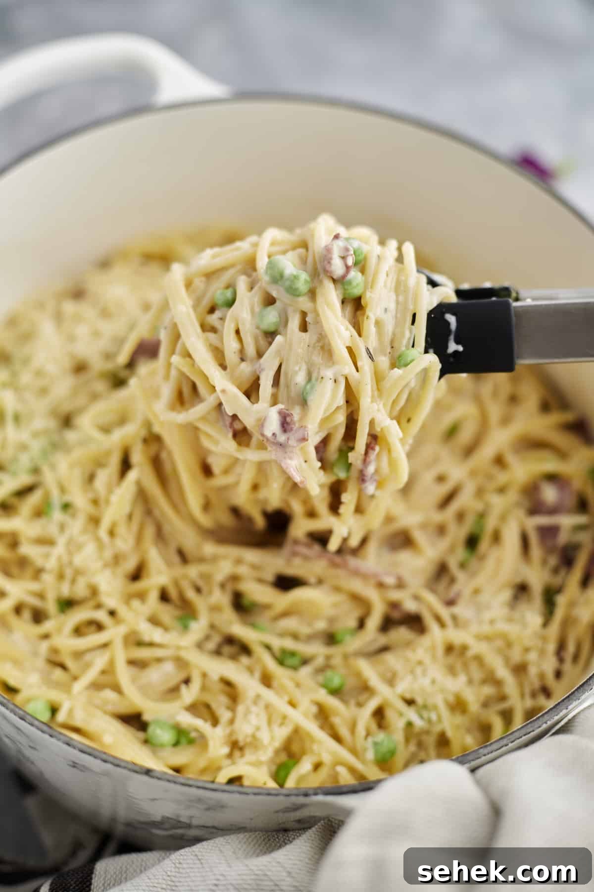 One-Pot Spaghetti Carbonara: Quick Creamy Classic Recipe 9 a pot of spaghetti carbonara with tongs lifting out a serving