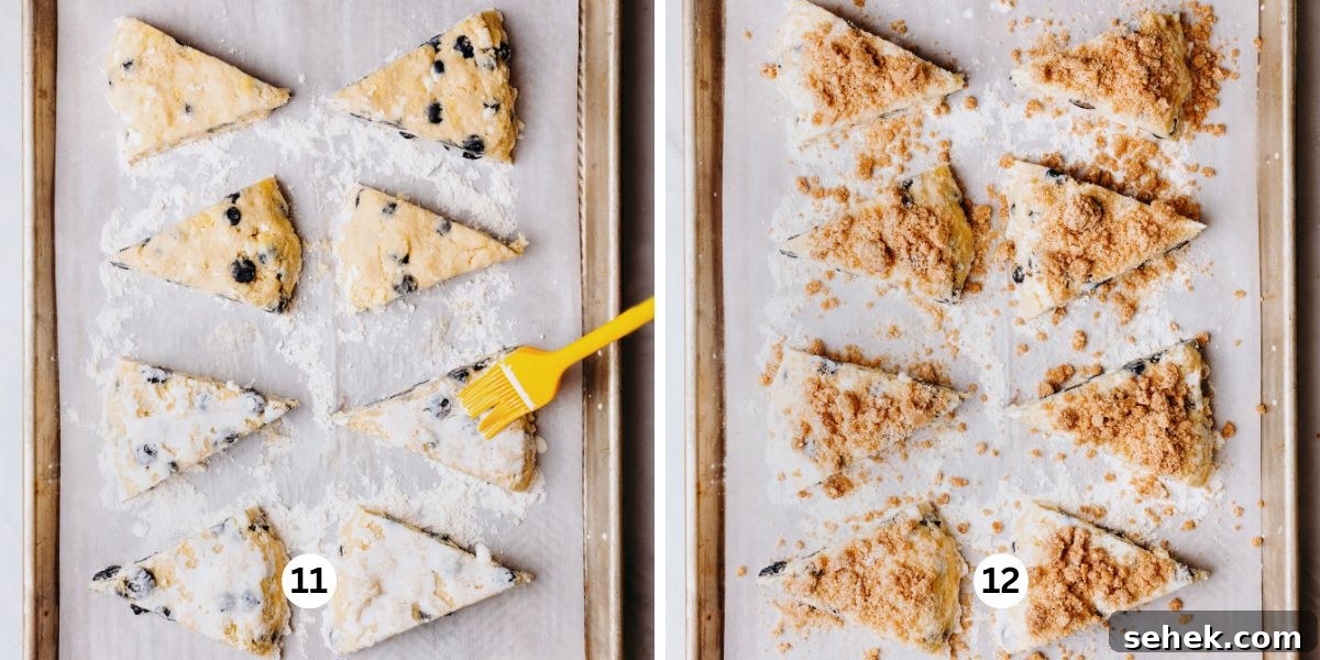 Brushing each lemon blueberry scone with a milk wash then topping with cinnamon sugar streusel on a floured, parchment paper lined baking sheet.
