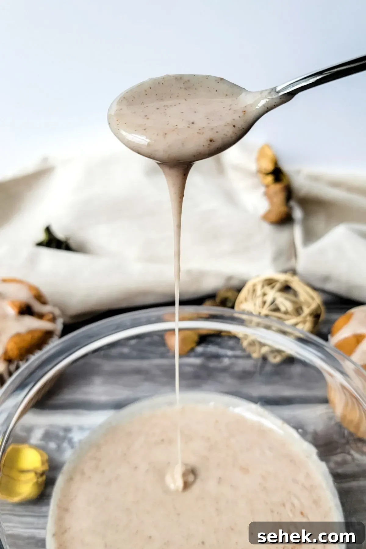 Cinnamon Spice Glaze Recipe for Cakes, Donuts & Pastries 3 Spoon dripping homemade glaze into a glass bowl.