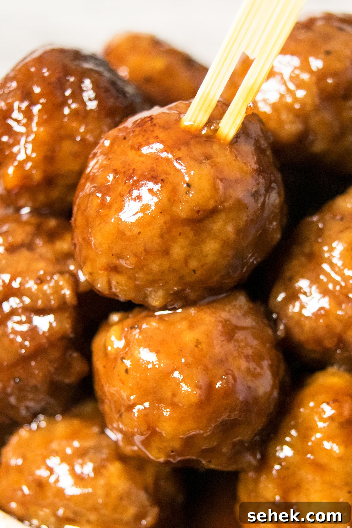 Bamboo toothpick pushed into a sweet and sour meatball- Closeup shot.