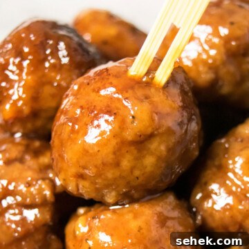 Bamboo toothpick being pushed into the best easy instant pot grape jelly meatballs.