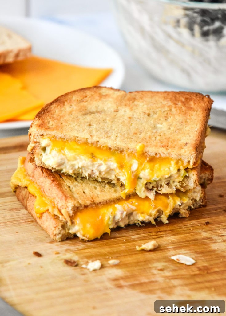 air fryer tuna melt cut in half stacked on a cutting board.