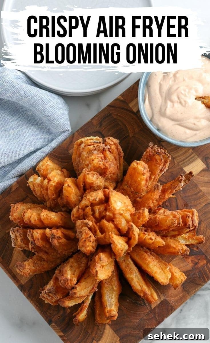 Crispy Air Fryer Blooming Onion Recipe for Perfect Appetizers 2 blooming onion on a wood cutting board with dipping sauce in the background.