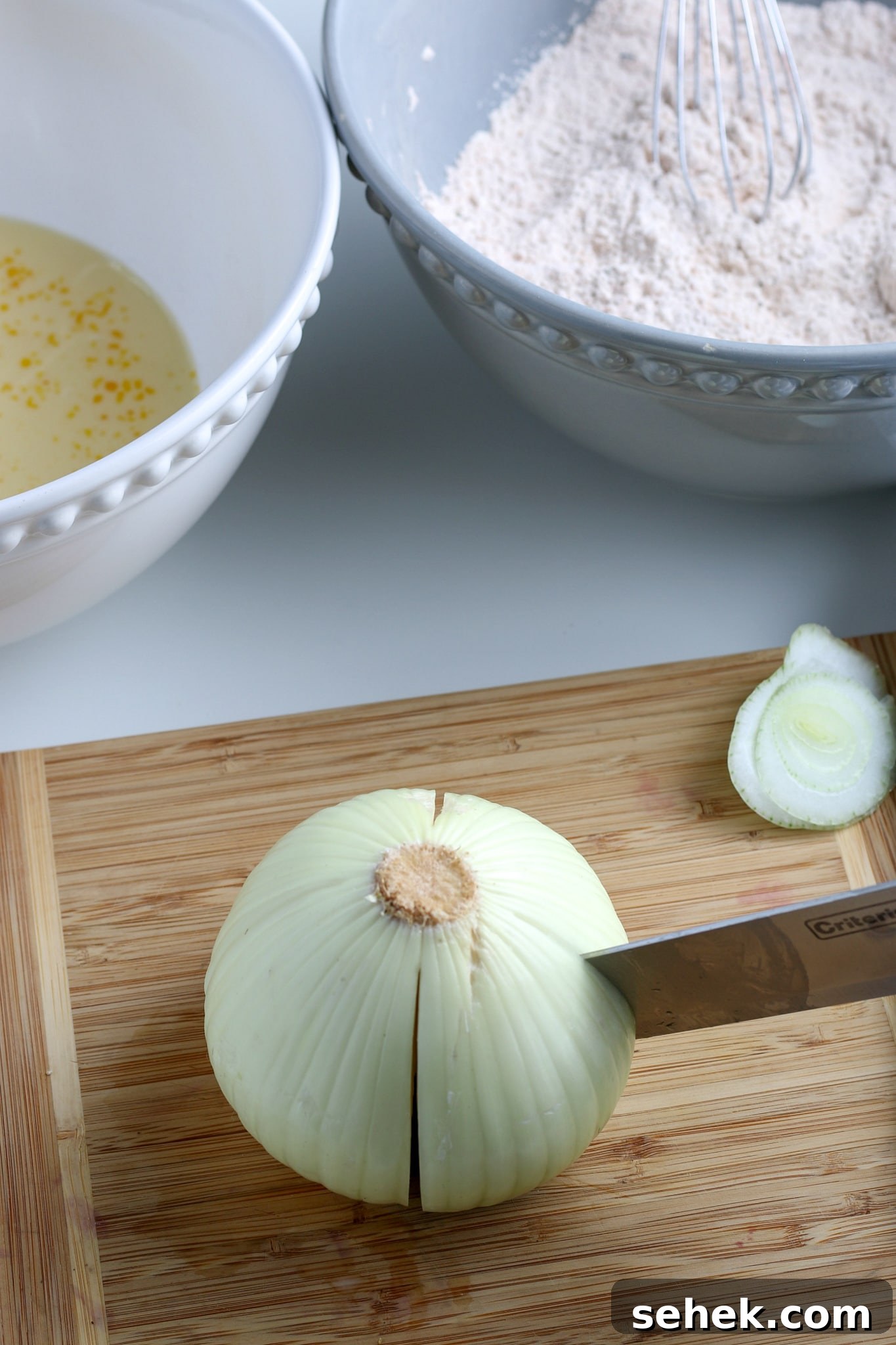 Crispy Air Fryer Blooming Onion Recipe for Perfect Appetizers 5 the onion being quartered on a wooden cutting board.