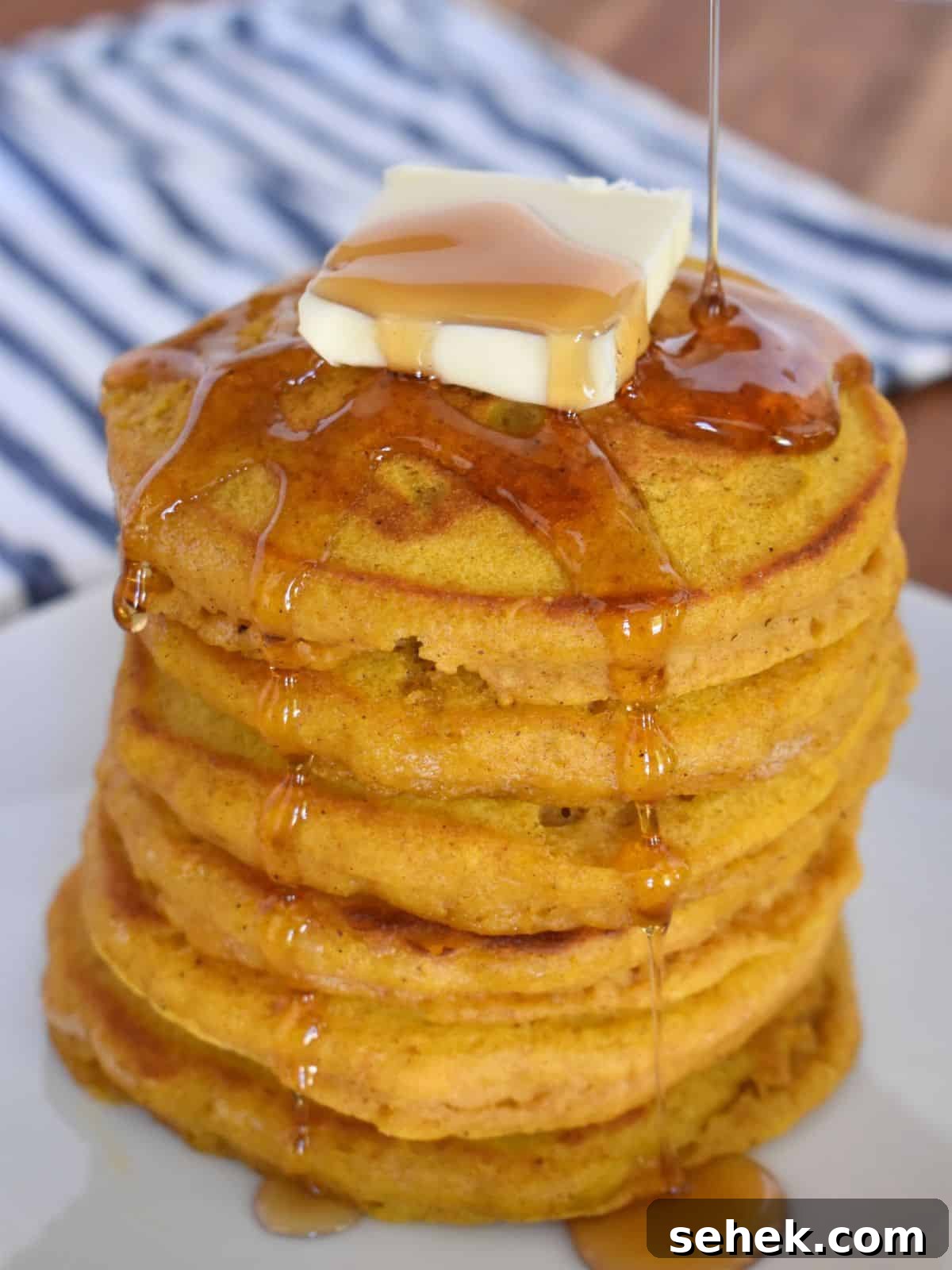 Fluffy Pumpkin Pancakes Using Pancake Mix – Quick Fall Recipe 2 Pumpkin Pancakes with pancake mix on a white plate with maple syrup pouring on top.