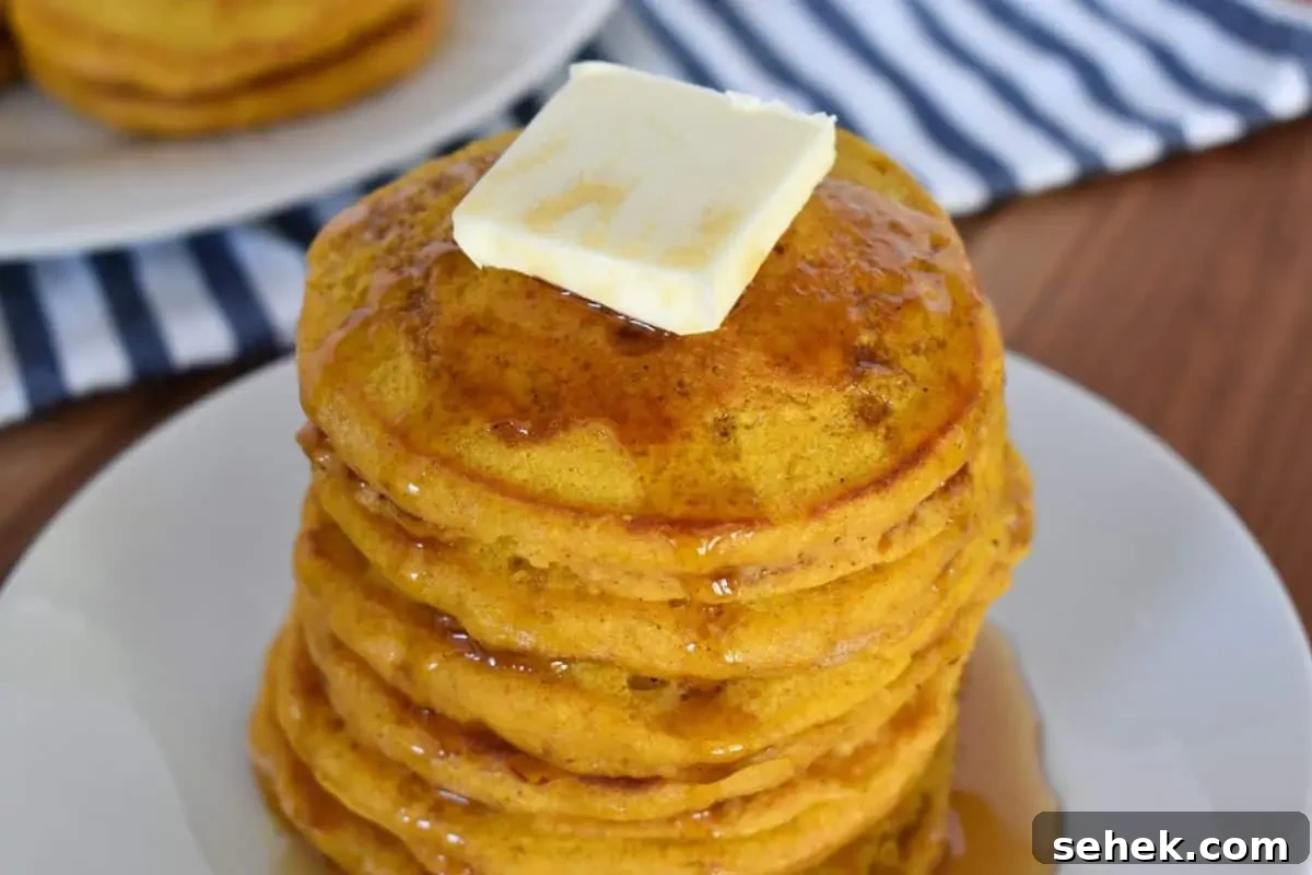 Fluffy Pumpkin Pancakes Using Pancake Mix – Quick Fall Recipe 7 Pumpkin pancakes with pancake mix on a white plate with a striped napkin in the background.