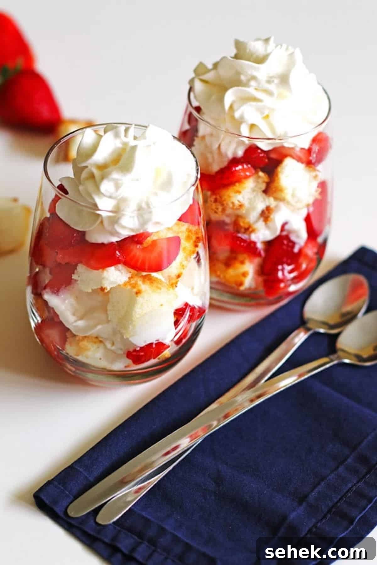 Strawberry Angel Food Shortcake with Fresh Whipped Cream 2 Two glasses of angel food cake strawberry shortcake topped with whipped cream.