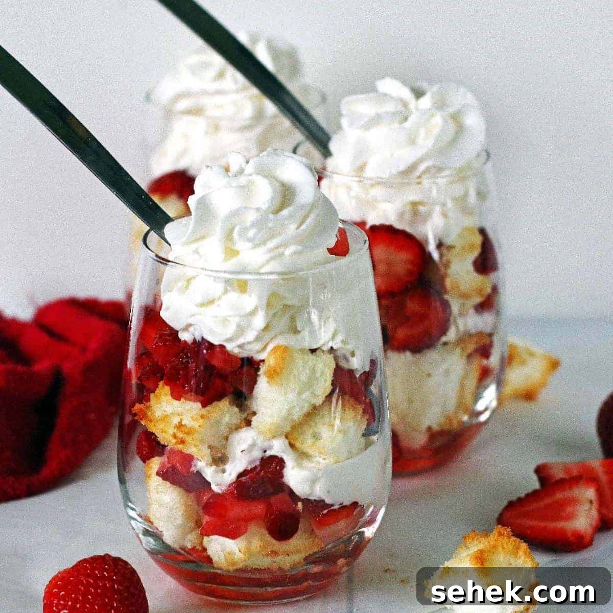 Strawberry Angel Food Shortcake with Fresh Whipped Cream 11 Two angel food cake strawberry shortcakes in stemless wine glasses topped with whipped cream.