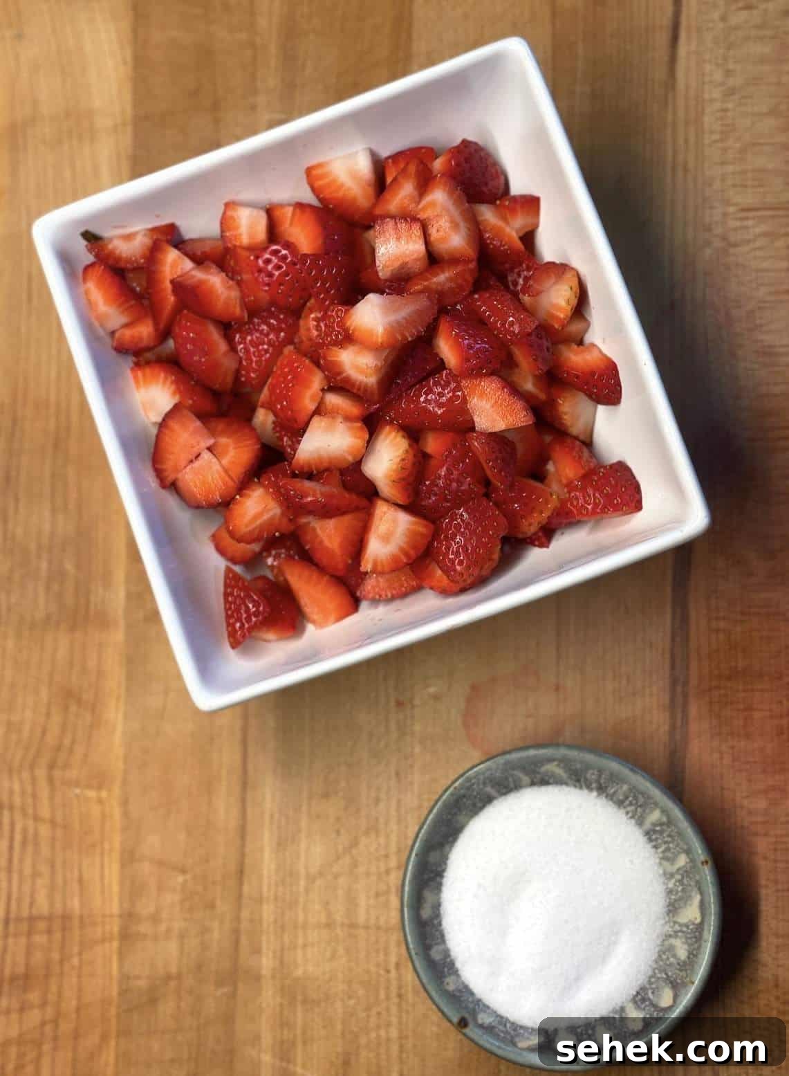 Strawberry Angel Food Shortcake with Fresh Whipped Cream 5 A bowl of strawberries and a bowl of sugar before being mixed together.