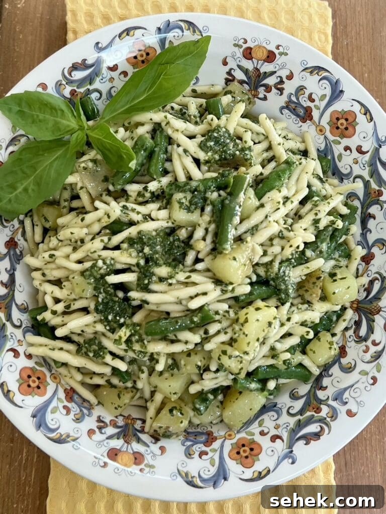 Trofie al Pesto Genovese with Potatoes and Green Beans 2 Trofie al pesto genovese in decorative bowl with basil sprig garnish.
