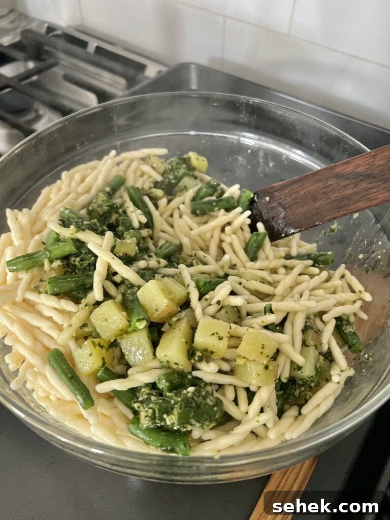Trofie al Pesto Genovese with Potatoes and Green Beans 11 Pasta with Pesto Green Beans and Potatoes in bowl with wooden spatula.