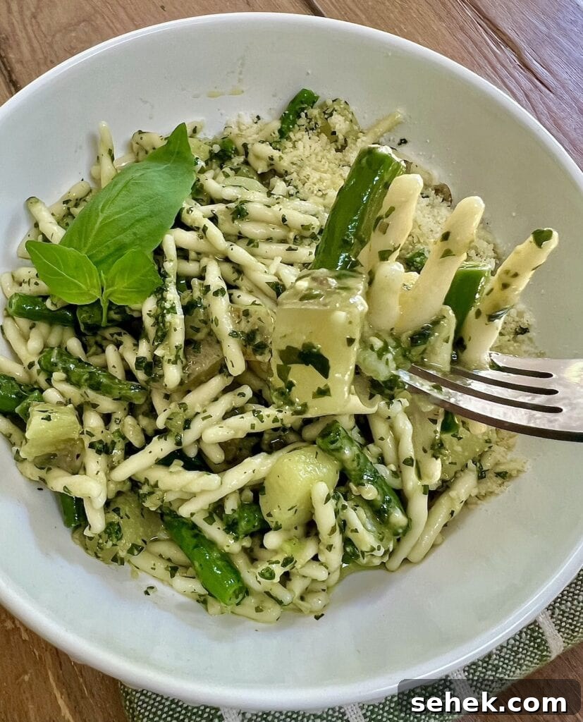 Trofie al Pesto Genovese with Potatoes and Green Beans 15 Close up of trofie al pesto genovese on fork over bowl of it.