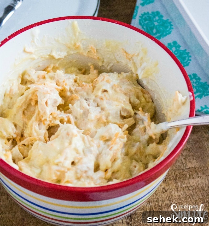 Creamy Cheesy Chicken Enchiladas with Melted Mexican Cheese 4 Chicken enchilada filling mixing together in mixing bowl.