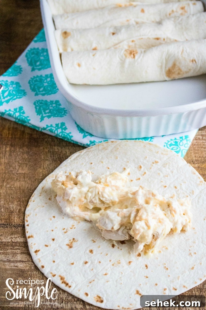 Creamy Cheesy Chicken Enchiladas with Melted Mexican Cheese 5 Open flour tortilla with filling for chicken enchiladas added.