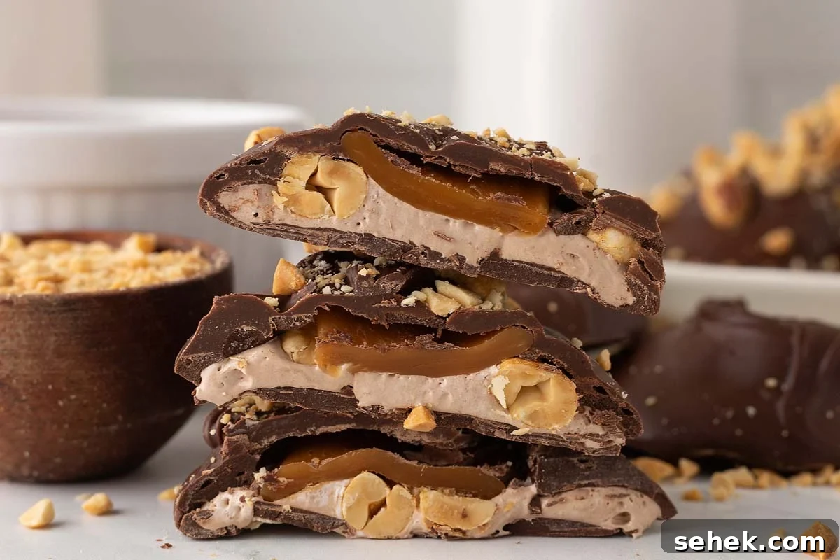 Close-up of a stack of homemade Snickers bites, revealing the irresistible layers of chocolate-covered caramel, peanuts, and nougat inside.